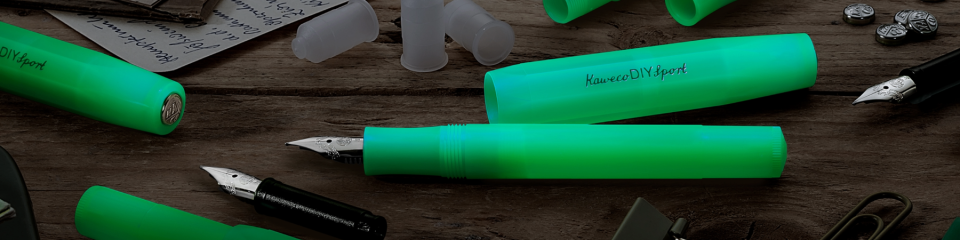 Kaweco DIY Sport fyllepenner i selvlysende grønn farge, delvis demontert på et bord med penndeler og skriveutstyr.