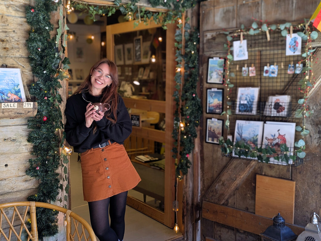 Kunstner Anna K Bjørdal (AKB) står utenfor butikken sin på Bryggen i Bergen