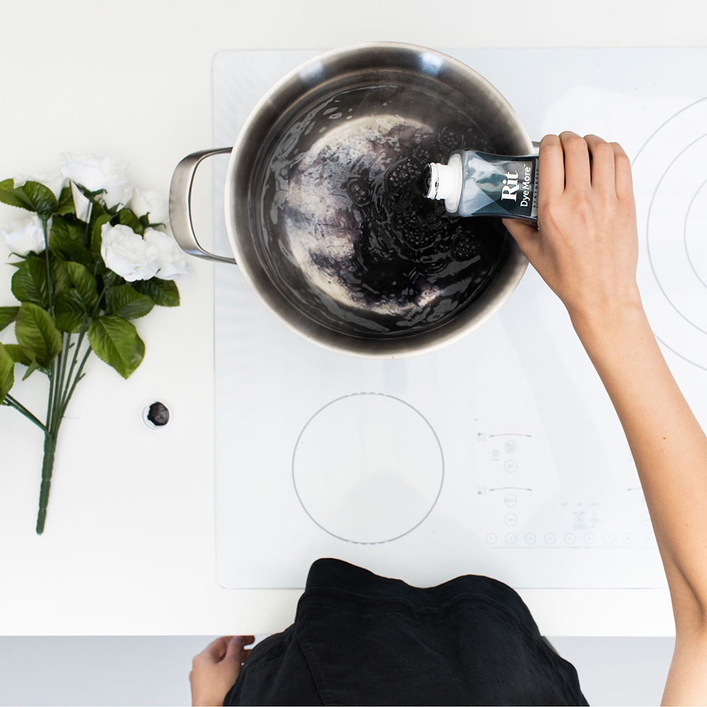 Hånd heller svart Rit-farge i en stålkjele med vann sett ovenfra.