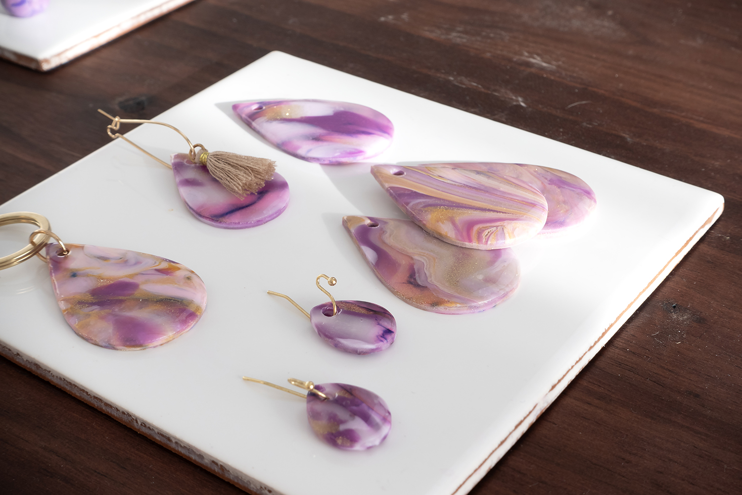 Smykkedeler av Cernit-leire i lilla, rosa og gullmarmorert mønster på hvit flis.