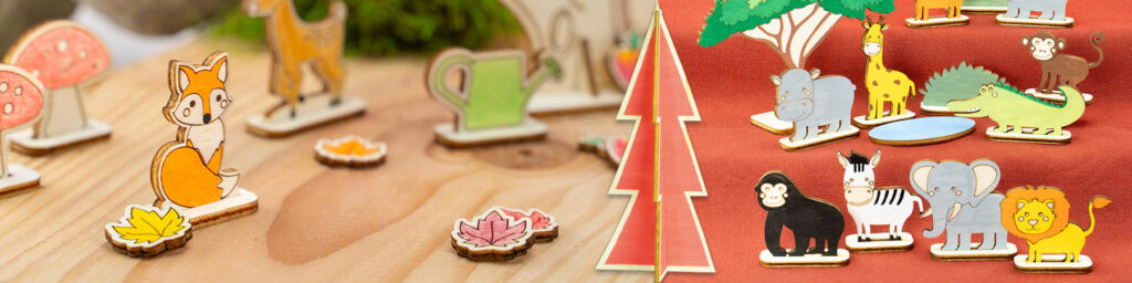 Fargerike trefigurer av skogs- og savannedyr står på bord og rød bakgrunn med trær i bakgrunnen.
