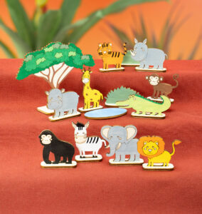 Fargerike trefigurer av savannedyr står oppstilt på rød bakgrunn.