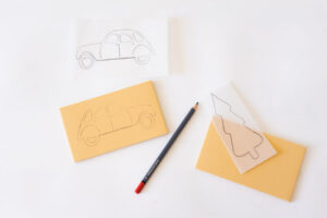 Skisser av bil og juletre overføres til linoplater sammen med en blyant.