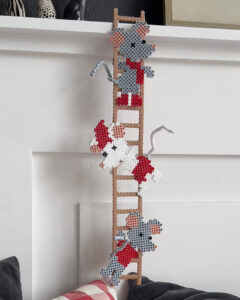 Perlede figurer av mus festet til en brun stige mot en hvit vegg.