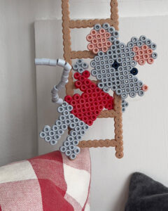 Hama-perlemus i rødt og grått henger på en brun perlestige.