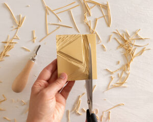 Hånd som klipper til en utskåret gummiplate omgitt av gummirester.