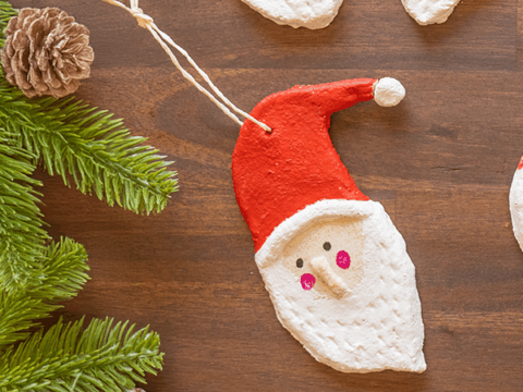 Utsnitt av nissefigurer i trolldeig med snor, arrangert på trebord sett ovenfra.