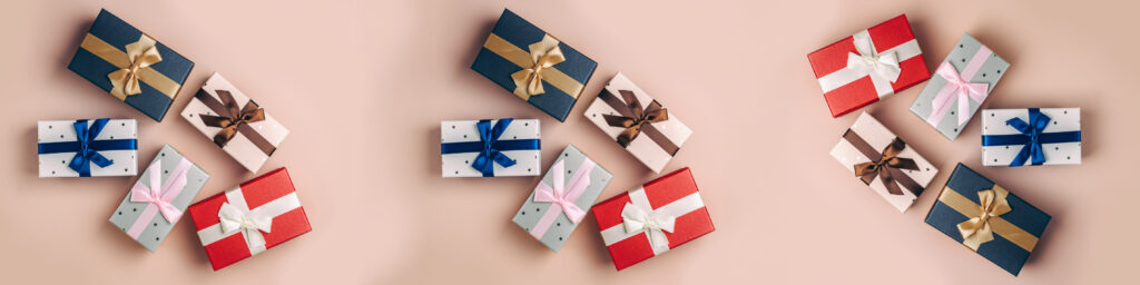 Flere gaveesker i ulike størrelser arrangert på lys rosa bakgrunn, sett ovenfra.