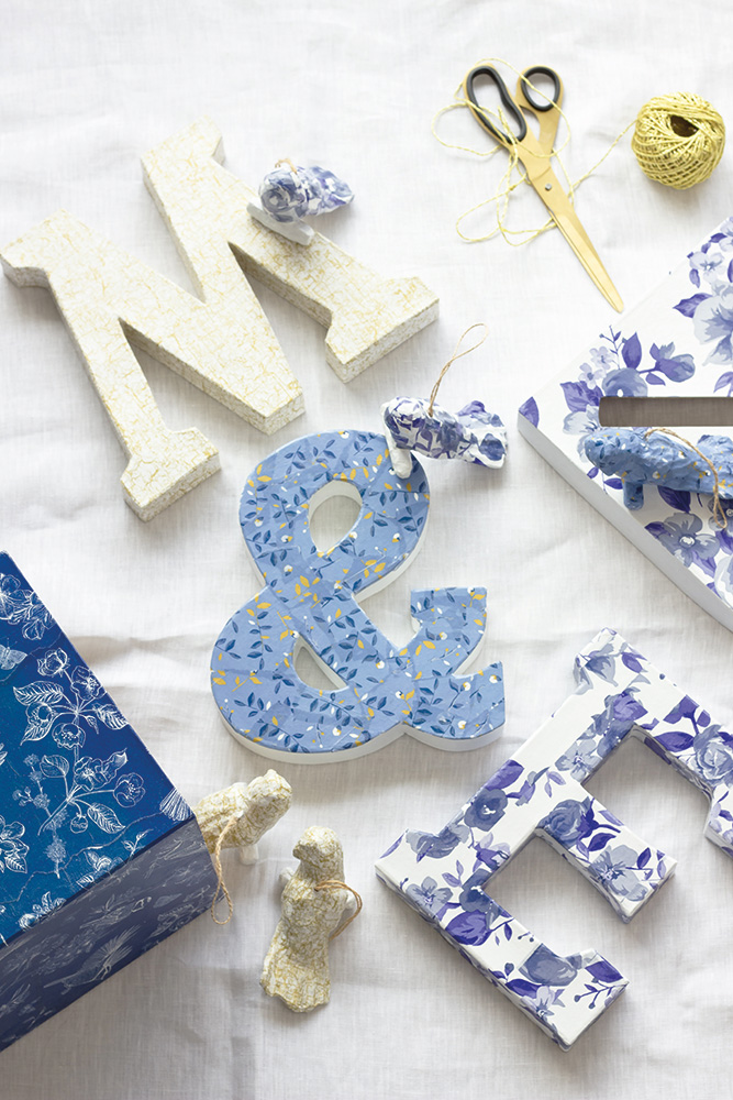 Dekorerte bokstaver og symboler med decoupage på tekstilbakgrunn.