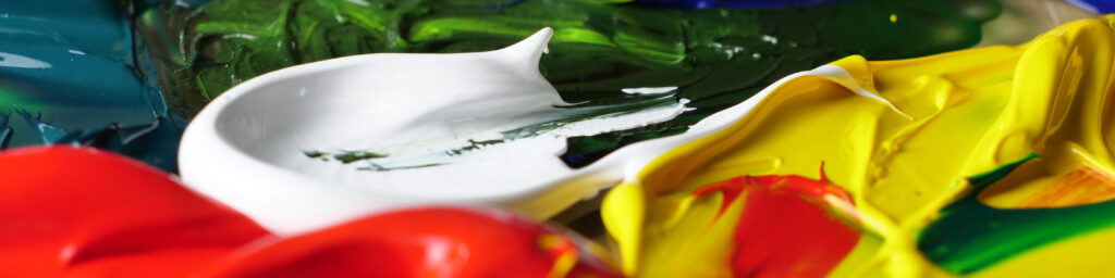 Nærbilde av tykk maling i rødt, gult, grønt og hvitt, lagt i myke, flytende former.