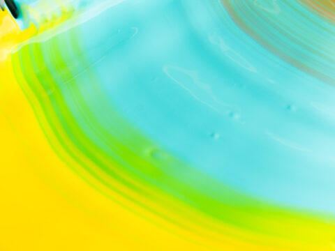 Nærbilde av flytende maling i sterke farger som blandes i buede strøk.