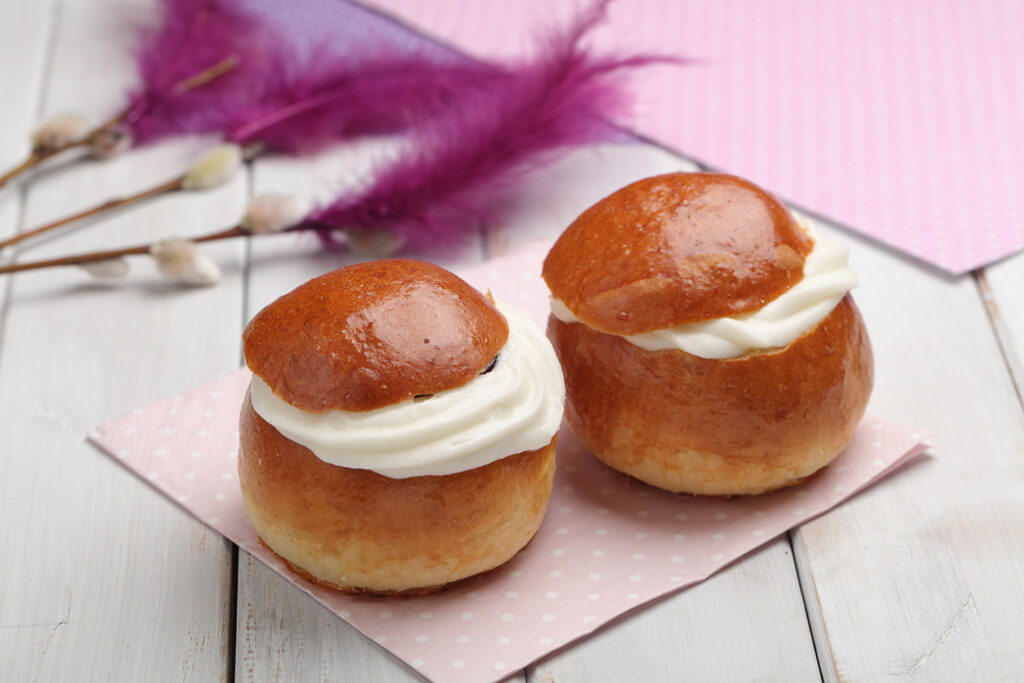 To fastelavnsboller med krem på rosa serviett.